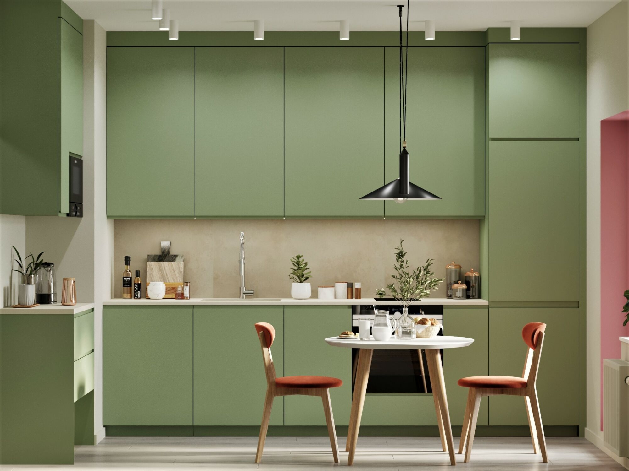 Flat Front or Slab. A modern kitchen with sage green flat front cabinets, a light-colored backsplash, and a small dining area with a white table and an orange-cushioned chair.